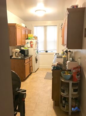 Evanston apartment for rent - a small kitchen with wooden cabinets and a white refrigerator